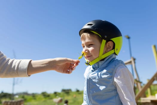 Child smelling flower given by mother at playground wearing helmet