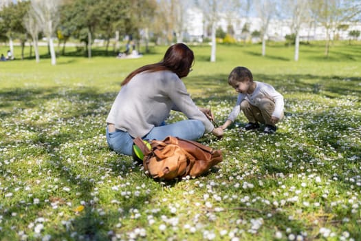 Mother and daughter enjoying a sunny day picking daisies in a park