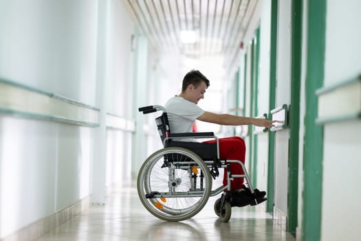 Young teenage boy smiling while sitting in a wheelchair in a hospital hallway. Rehabilitation and positivity concept
