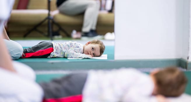 Young boy on a therapy mat during a physiotherapy session, engaging in a supervised stretching activity.