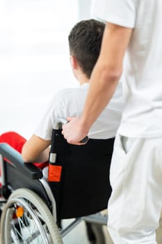 Medical staff in white uniforms assist a patient in a wheelchair in a bright hospital corridor. Concept of healthcare and assistance.