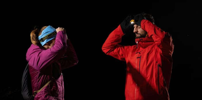 A woman provides headlamp-assisted first aid to a man outdoors in the dark, showcasing emergency preparedness in extreme conditions.