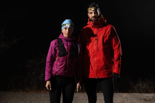 Couple equipped with headlamps explore a forest in total darkness, with beams of light cutting through the night air.