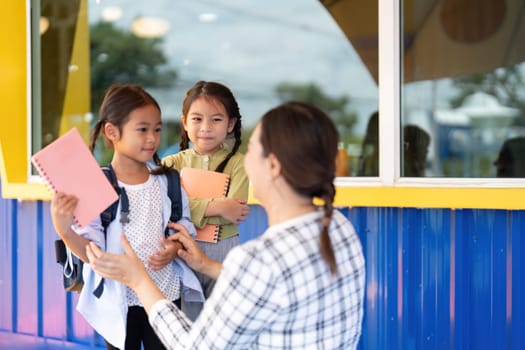 Two young girls share a moment with their teacher, showcasing the warmth and support of the back-to-school environment.