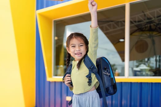 A young girl proudly raises her fist in celebration as she embarks on her school journey, embodying the spirit of back-to-school excitement.