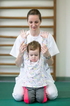 Female physiotherapist helping a young child with physical exercises in a rehabilitation center. Pediatric therapy and development concept.