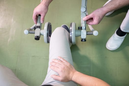 Top down view of a person using a rehabilitation machine for leg therapy, focusing on muscle training and mobility.