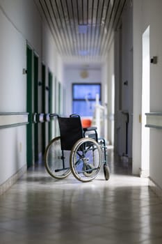 Unattended wheelchair positioned in a bright hospital corridor. Concept of accessibility and patient transport.