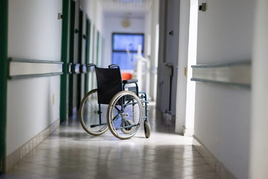 Unattended wheelchair positioned in a bright hospital corridor. Concept of accessibility and patient transport.
