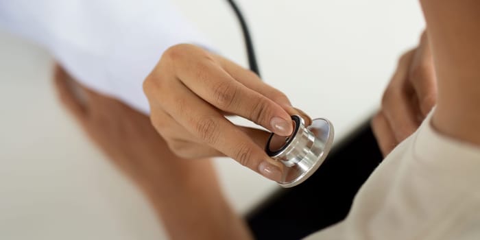 A healthcare professional checks a patient's heart rate with a stethoscope, emphasizing health monitoring.