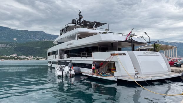 Budva, Montenegro - May 21, 2025: Elegant yacht Aquarius is anchored in calm waters with stunning mountain scenery