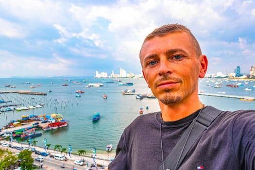 Handsome Man Tourist and Traveler with the Pattaya City Bay Beach Nature Jungle Pier and Boats Panorama View in Pattaya Bang Lamung Chon Buri Thailand.