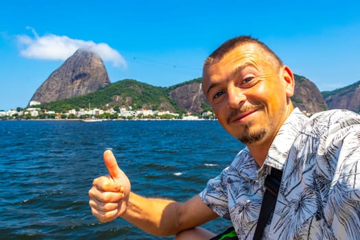 Handsome Tourist Traveler Man is Posing at the Sugarloaf Sugar Loaf Mountain Hill Rock Pao de Acucar Panorama View in the Urca Village of Rio de Janeiro Brazil.