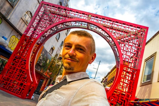 Man Handsome Tourist at the China Town Chinatown Red Entrance Welcome Gate to Tourst Street in Centro Historico Mexico City Mexico.