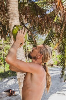 Man drinking from a coconut on the beach in Playa del Carmen Quintana Roo Mexico.