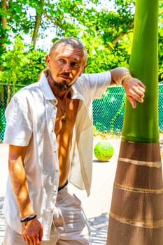 Handsome man with a palm tree in tropical nature in Playa del Carmen Quintana Roo Mexico.