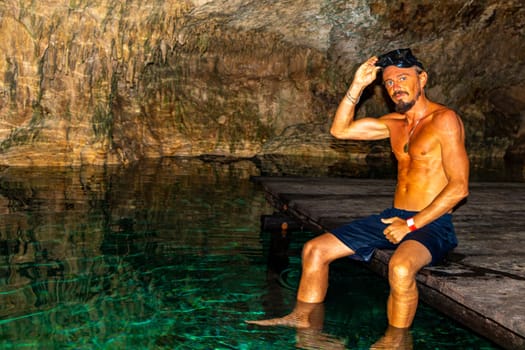 Man male tour guide is swimming and snorkeling in the turquoise green blue water in a cenote Yaxmulito in Tulum Quintana Roo Mexico.