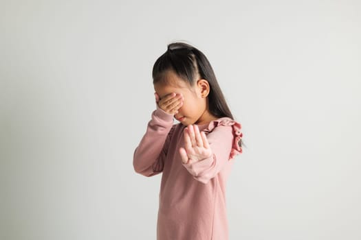 Stop hand of kindergarten child. Asian little kid girl doing stop sing gesture with palm of the hand at studio shot isolated on white background, child raised hand five fingers