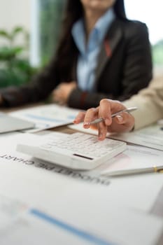 Close-up view of hands using a calculator and reviewing financial documents in a professional setting.