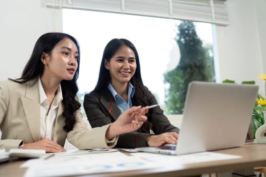Two business professionals collaborate on a laptop, sharing ideas and strategies in a modern office environment.