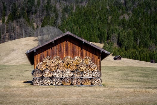 Wooden barn with firewood piles seen in the alps of Bavaria