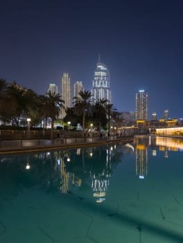 UAE, Dubai, 26 September 2024: The famous shopping center Dubai Mall and Burj Khalifa skyscraper at dusk, Dubai's sights and skyscrapers illuminated at night, palm trees. High quality photo