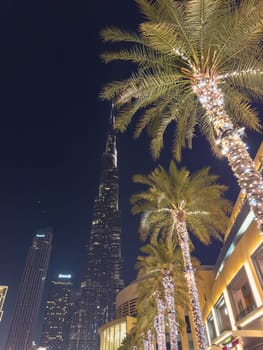 UAE, Dubai, 26 September 2024: The famous shopping center Dubai Mall and Burj Khalifa skyscraper at dusk, Dubai's sights and skyscrapers illuminated at night, palm trees. High quality photo