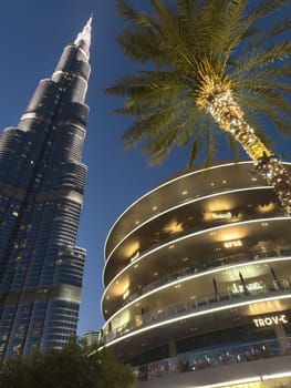 UAE, Dubai, 26 September 2024: The famous shopping center Dubai Mall and Burj Khalifa skyscraper at dusk, Dubai's sights and skyscrapers illuminated at night, palm trees. High quality photo