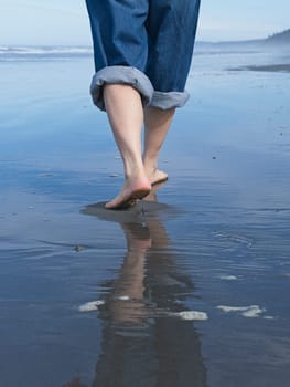 A closeup conceptual photos of a woman's feet shown barefooted walking on the beach by the pacific ocean in Washington.