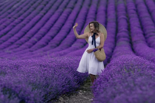 A woman stands in a field of purple flowers, wearing a white dress and a straw hat. She is enjoying the beauty of the flowers and the peacefulness of the setting