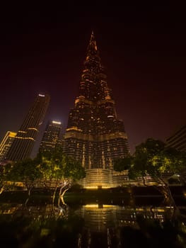 UAE, Dubai, 26 September 2024: The famous shopping center Dubai Mall and Burj Khalifa skyscraper at dusk, Dubai's sights and skyscrapers illuminated at night, palm trees. High quality photo