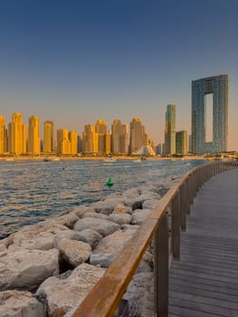 UAE, Dubai, 21 September 2024: Lively navigation of Dubai Marina along the waterfront against the backdrop of the beach and skyscrapers at sunset, boats and yachts with people on board. High quality photo