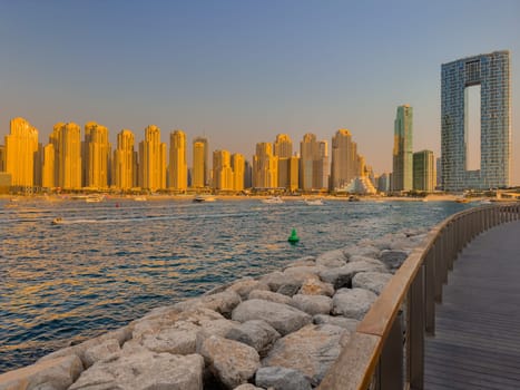 UAE, Dubai, 21 September 2024: Lively navigation of Dubai Marina along the waterfront against the backdrop of the beach and skyscrapers at sunset, boats and yachts with people on board. High quality photo