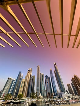 UAE, Dubai, 29 September 2024: Skyscrapers from Dubai harbor marina at sunny day, luxury yachts and boats are moored in port. High quality photo