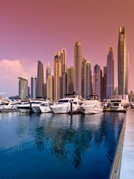 UAE, Dubai, 29 September 2024: Skyscrapers from Dubai harbor marina at sunny day, luxury yachts and boats are moored in port. High quality photo
