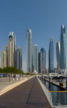 UAE, Dubai, 29 September 2024: Skyscrapers from Dubai harbor marina at sunny day, luxury yachts and boats are moored in port. High quality photo