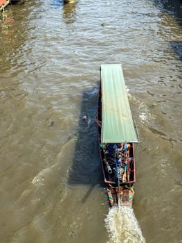 Bangkok, Thailand - November 12, 2024: Floating market with boats selling Thai local food, riverside bazaar with market vendors offering delicious fresh exotic produce, tourism.