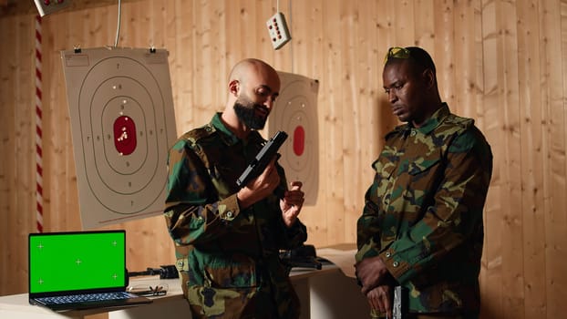 Mockup laptop next to soldiers in shooting range training discussing about weapons. Isolated screen notebook in firing range next to military units having conversation, camera A