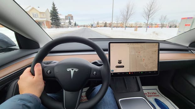 Ottawa, ON Canada - 12.27.2024: Driver s Perspective Navigating a Suburban Street with Modern electric Tesla Vehicle Tech and Winter Scenery.