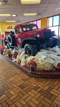 Syracuse, NY USA - 12.23.2023: Vintage Red Truck Display with Holiday Decor, Classic Vehicle on Elevated Platform