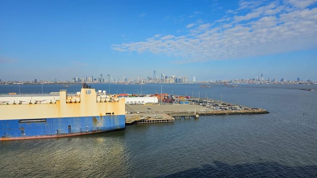 New York, NY USA - 02.09.2024: Cargo Ship Docked with Distant City Skyline Views Amidst Clear Skies And Waters.