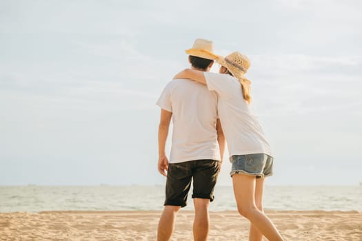 Back Asian couple standing hugging together on the beach, Happy young woman embracing her boyfriend seaside honeymoon vacation background, couple in love resting on sea