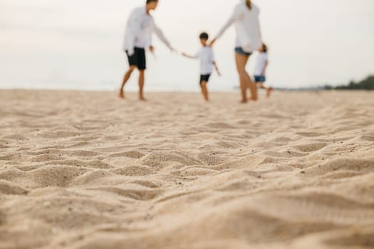 Smiling father and mother with son and daughter having fun on the beach. Running playing and laughing creating cheerful moments of family bonding and joy during summer. Family on beach vacation