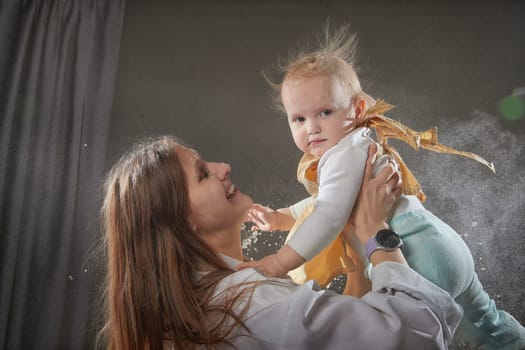 A mother and daughter joyfully engage in a flour-filled moment, creating memories in a cozy kitchen setting.