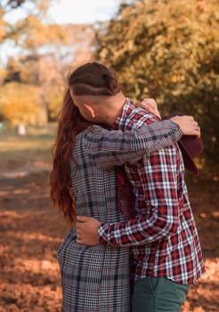 young couple in love hugging in autumn park. against the background of autumn trees. concept of falling in love, relaxation