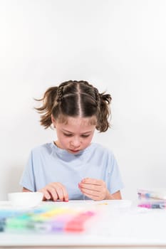 Little girl enjoys crafting colorful bracelets with vibrant clay beads set.