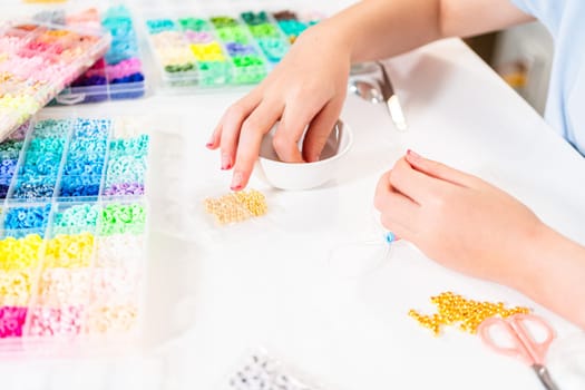 Little girl enjoys crafting colorful bracelets with vibrant clay beads set.
