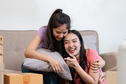 A happy diverse couple embraces on the couch, laughing and enjoying each other's company amidst moving boxes.