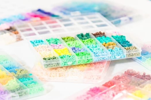 Assorted clay bead boxes neatly arranged on a white table, awaiting a creative kids' craft project.