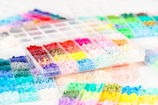 Assorted clay bead boxes neatly arranged on a white table, awaiting a creative kids' craft project.